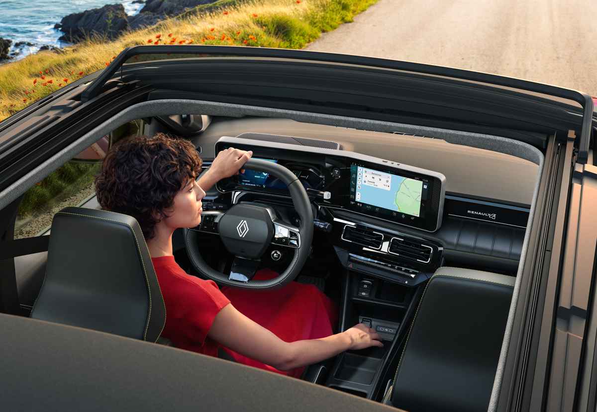 Interior del habitáculo del Renault 4 Plein Sud. Se observa a la conductora disfrutando del techo de lona abierto que permite la abundante entrada de luz natural, resaltando el moderno tablero con pantallas digitales duales y texturas oscuras.
