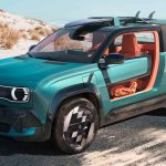 Vista frontal en ángulo del prototipo Renault 4 JP4x4 Concept color verde esmeralda estacionado en la arena. Destaca su diseño tipo buggy sin puertas con un llamativo interior naranja, y un techo abierto que soporta tablas de surf.