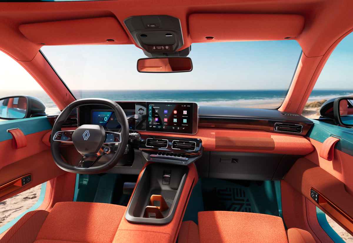 Tablero moderno y digital del Renault 4 JP4x4 Concept. Destaca el diseño abierto del habitáculo sin puertas que ofrece vista directa a la playa, y los fuertes contrastes entre la consola central flotante color naranja y los detalles oscuros.