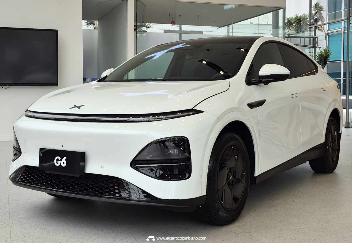 Vista frontal en ángulo de la SUV eléctrica Xpeng G6 color blanco exhibida en concesionario, destacando sus luces diurnas continuas, diseño aerodinámico y rines negros deportivos.