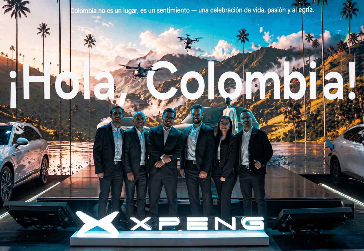 Grupo de directivos y representantes de Inchcape posando junto al emblema iluminado de Xpeng durante el evento de lanzamiento de la marca en Colombia, con el mensaje 