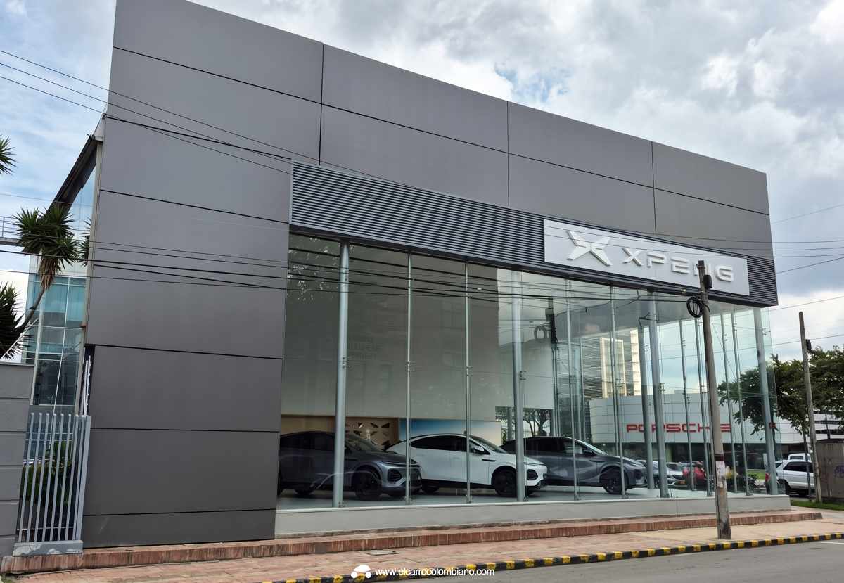 Fachada principal de la nueva vitrina comercial de Xpeng en Bogotá, estructurada con amplios ventanales de vidrio y paneles grises, exhibiendo los modelos eléctricos G6 y G9 en su interior.