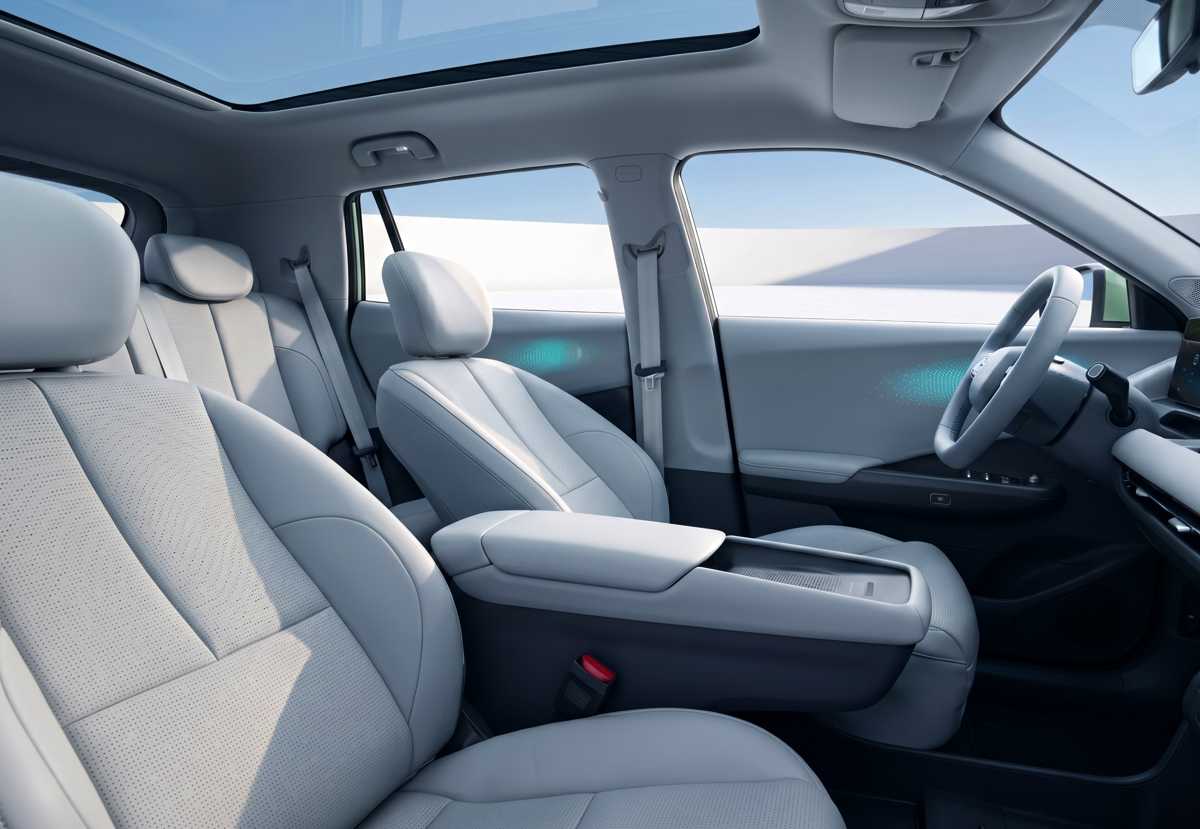 Asientos delanteros ergonómicos de la SUV Dongfeng Vigo, tapizados en cuero sintético gris claro, destacando el amplio apoyabrazos central flotante y la iluminación ambiental.