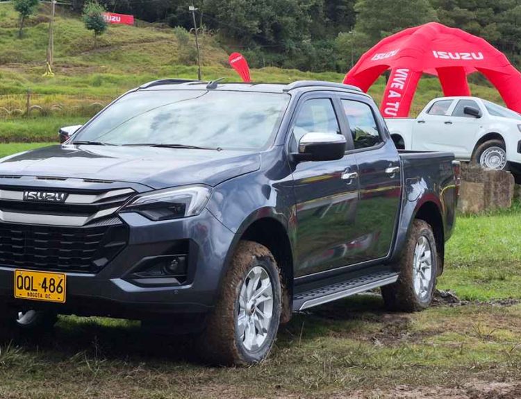 Vista frontal en tres cuartos de la nueva Isuzu Pickup 2027 color gris oscuro sobre una pista de barro, destacando su nueva parrilla y faros rediseñados en Colombia.