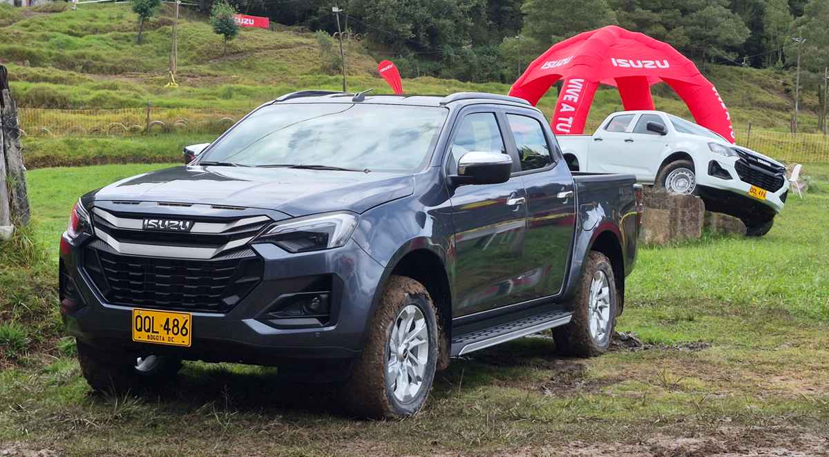 Vista frontal en tres cuartos de la nueva Isuzu Pickup 2027 color gris oscuro sobre una pista de barro, destacando su nueva parrilla y faros rediseñados en Colombia.