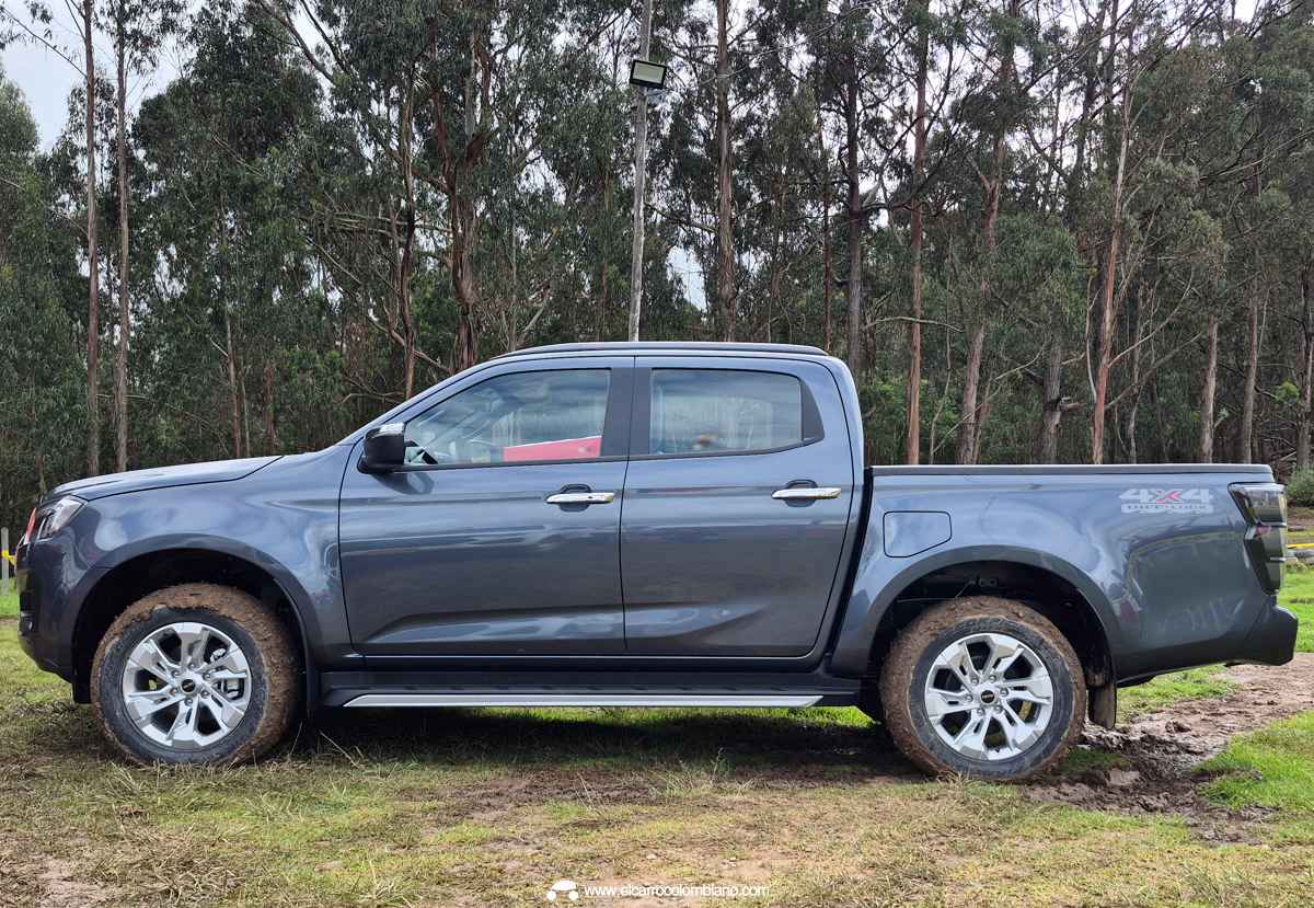 Perfil lateral de la Isuzu Pickup 2027 Doble Cabina en color gris, resaltando su altura al piso, rines de aluminio y estribos tras un recorrido por pista de barro.