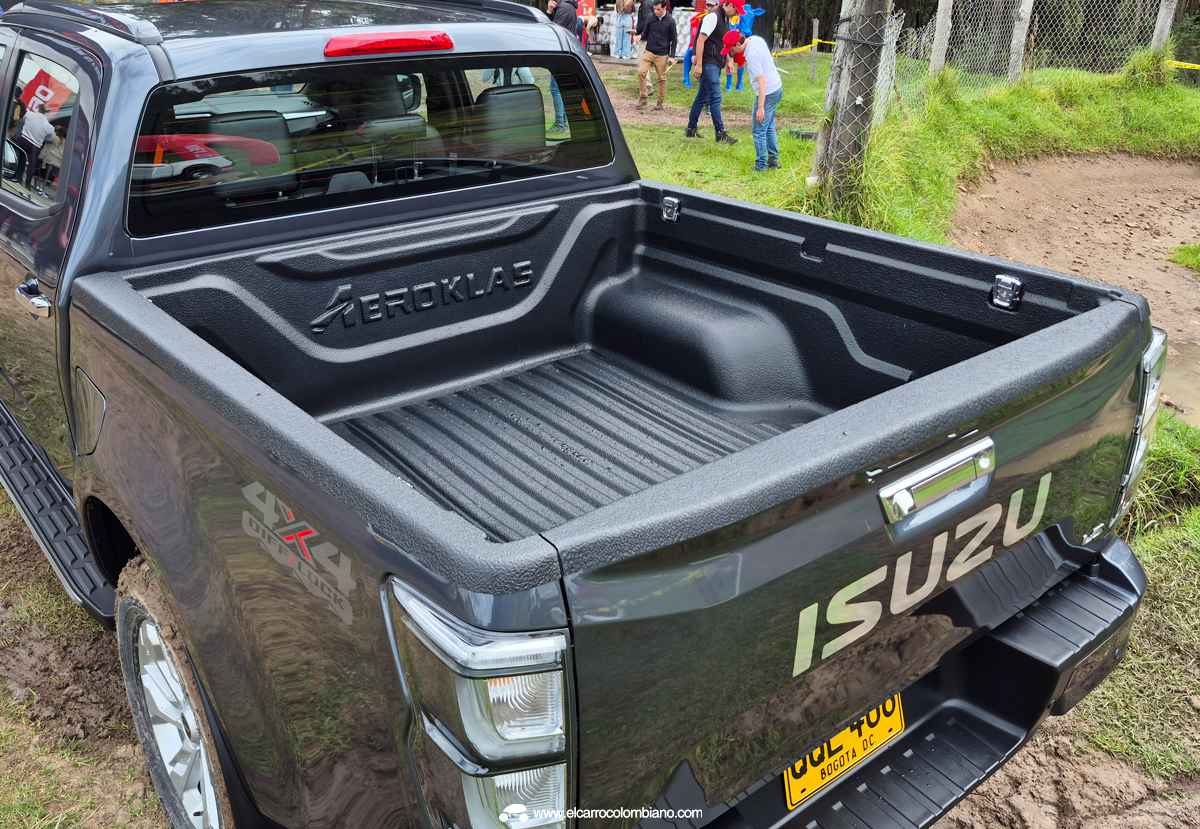 Área de carga o platón de la Isuzu Pickup 2027, equipada con recubrimiento protector oscuro y compuerta trasera cromada con la inscripción de la marca japonesa.