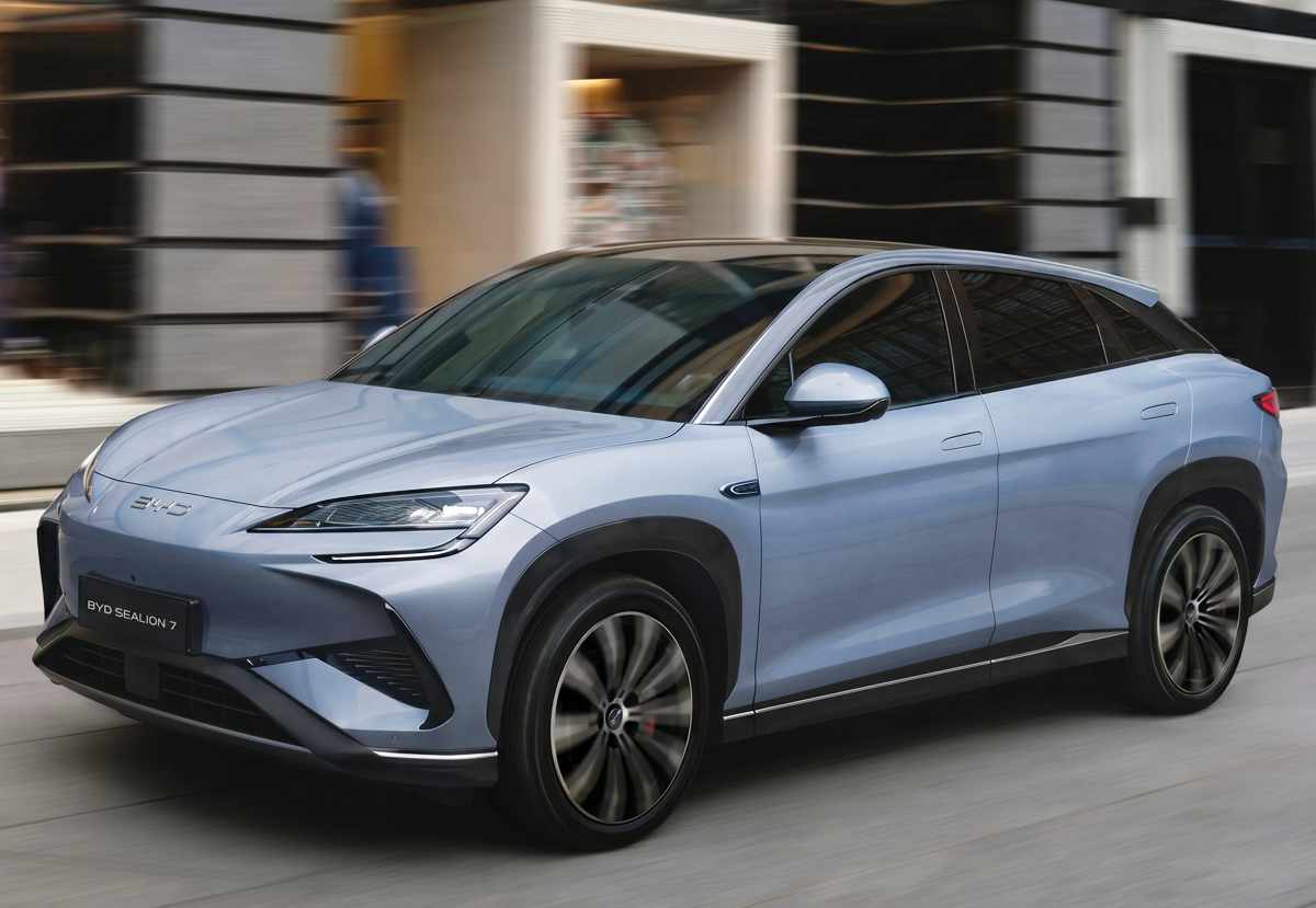 SUV eléctrico BYD Sealion 7 en color azul claro circulando dinámicamente por una calle urbana, modelo que también ajustó sus tarifas a la baja ante la guerra de precios.