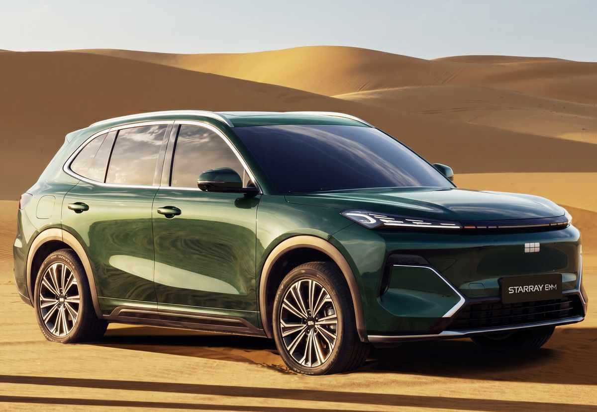 Perfil frontal de la nueva camioneta híbrida Geely Starray EM-i en tono verde oscuro profundo, posando en un entorno desértico con dunas de arena en el fondo.