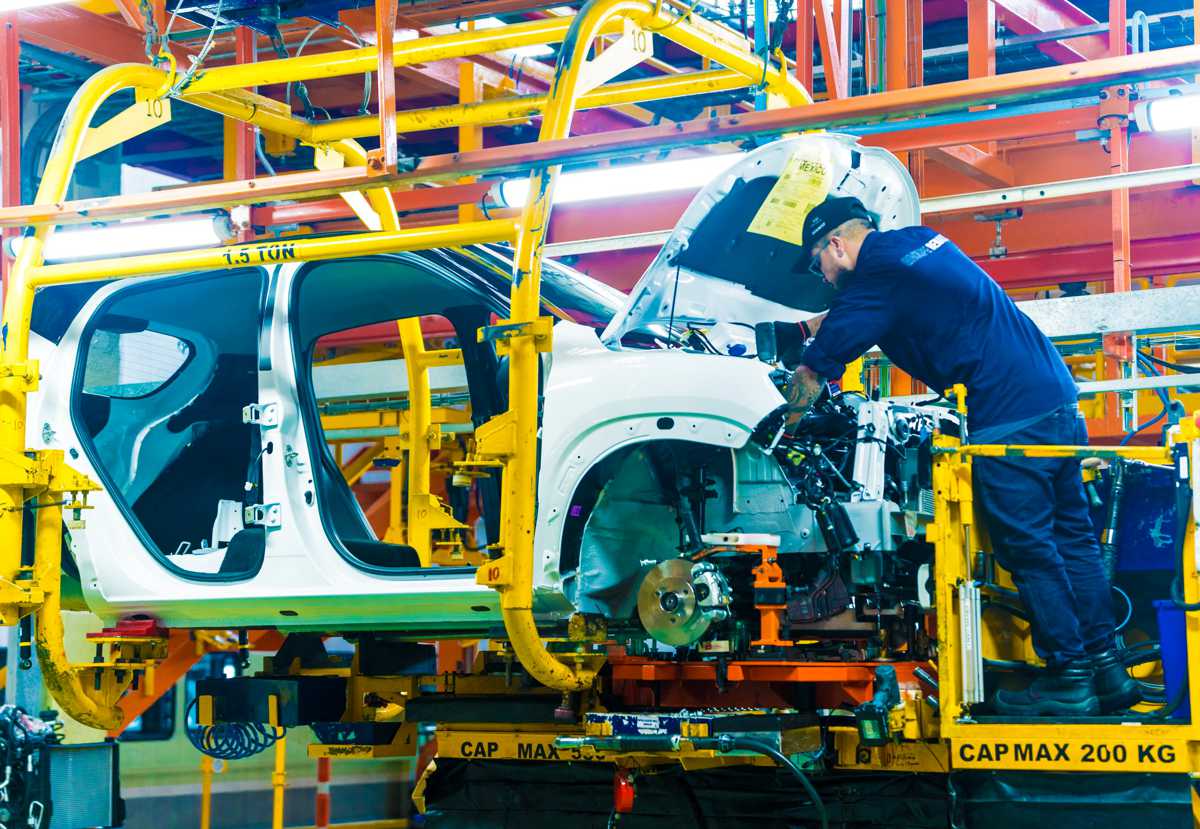 Operario trabajando en el vano motor de un vehículo sobre la línea de montaje aérea en las instalaciones de la fábrica Renault en Colombia.