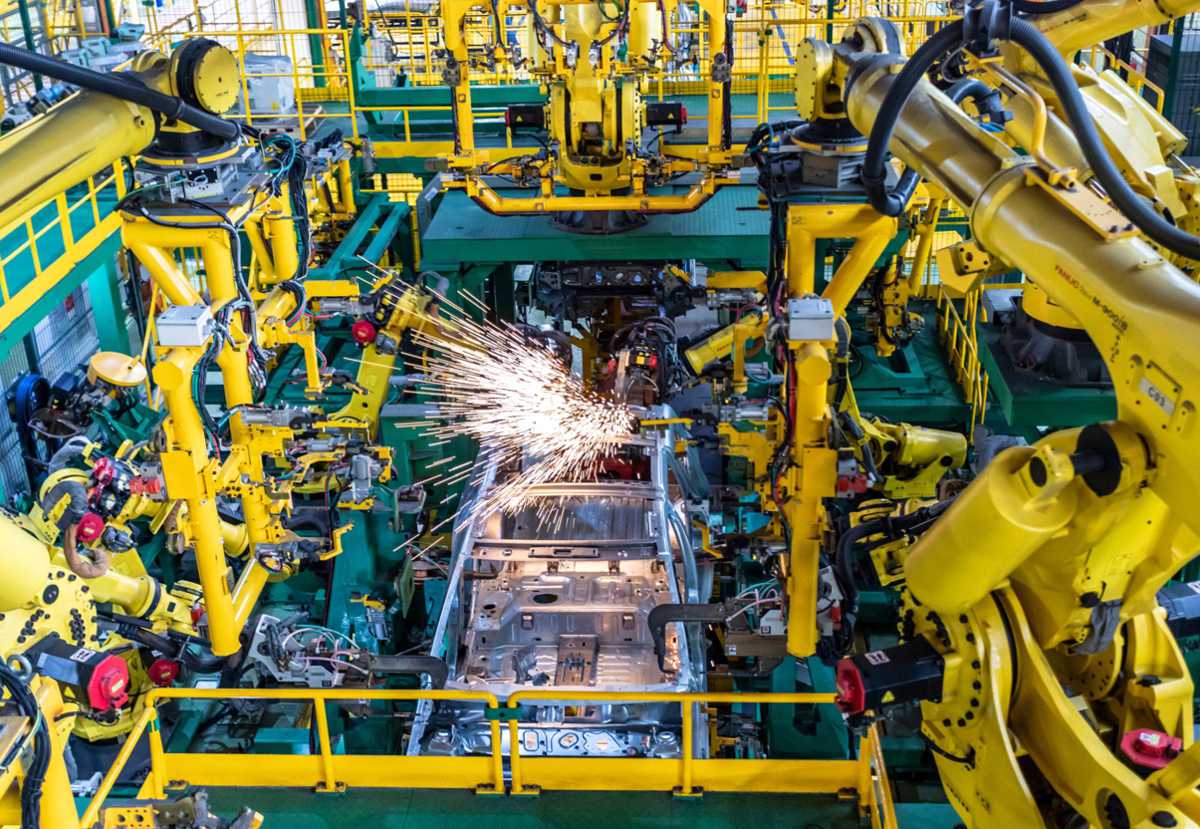 Brazos robóticos automatizados generando chispas durante el proceso de soldadura de carrocerías en la planta industrial de Envigado.