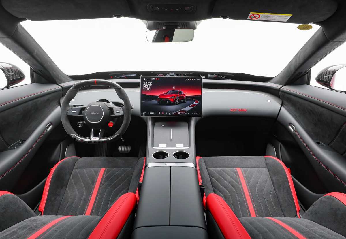 Puesto de conducción del Xiaomi YU7 GT, detallando el volante deportivo forrado en Alcantara, la gran pantalla multimedia central y los asientos con detalles rojos.