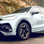 Nueva Volkswagen Tiguan e-TSI híbrida color blanco puro en movimiento sobre una carretera de montaña, destacando su renovado diseño frontal y rines aerodinámicos bitono.