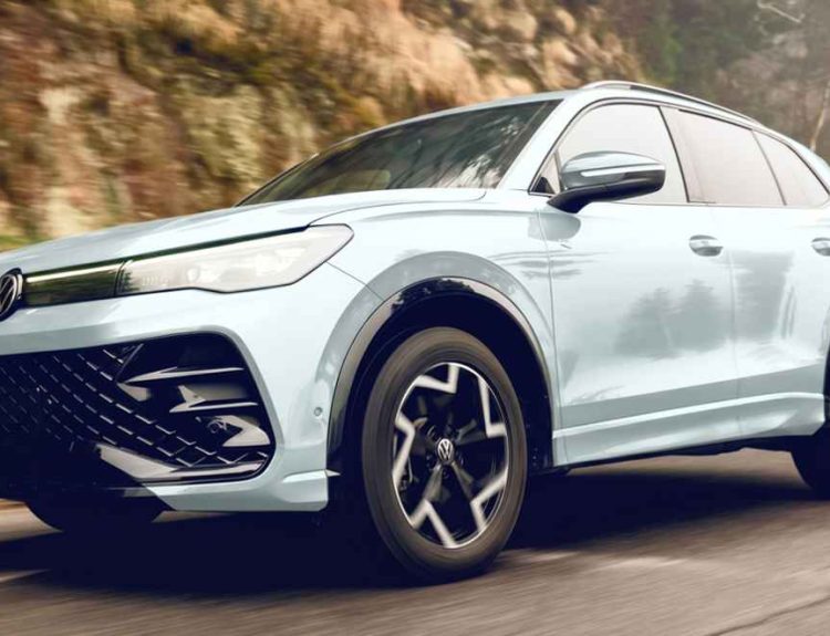 Nueva Volkswagen Tiguan e-TSI híbrida color blanco puro en movimiento sobre una carretera de montaña, destacando su renovado diseño frontal y rines aerodinámicos bitono.
