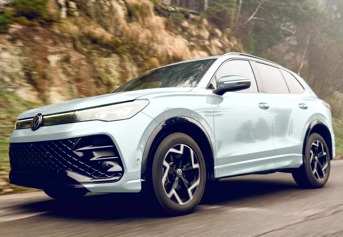 Nueva Volkswagen Tiguan e-TSI híbrida color blanco puro en movimiento sobre una carretera de montaña, destacando su renovado diseño frontal y rines aerodinámicos bitono.