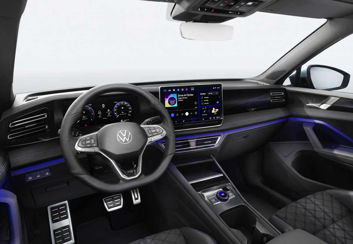 Puesto de conducción de la nueva Volkswagen Tiguan e-TSI híbrida, mostrando el volante deportivo forrado en cuero, panel digital, gran pantalla central táctil de 15 pulgadas y luz ambiental azul.