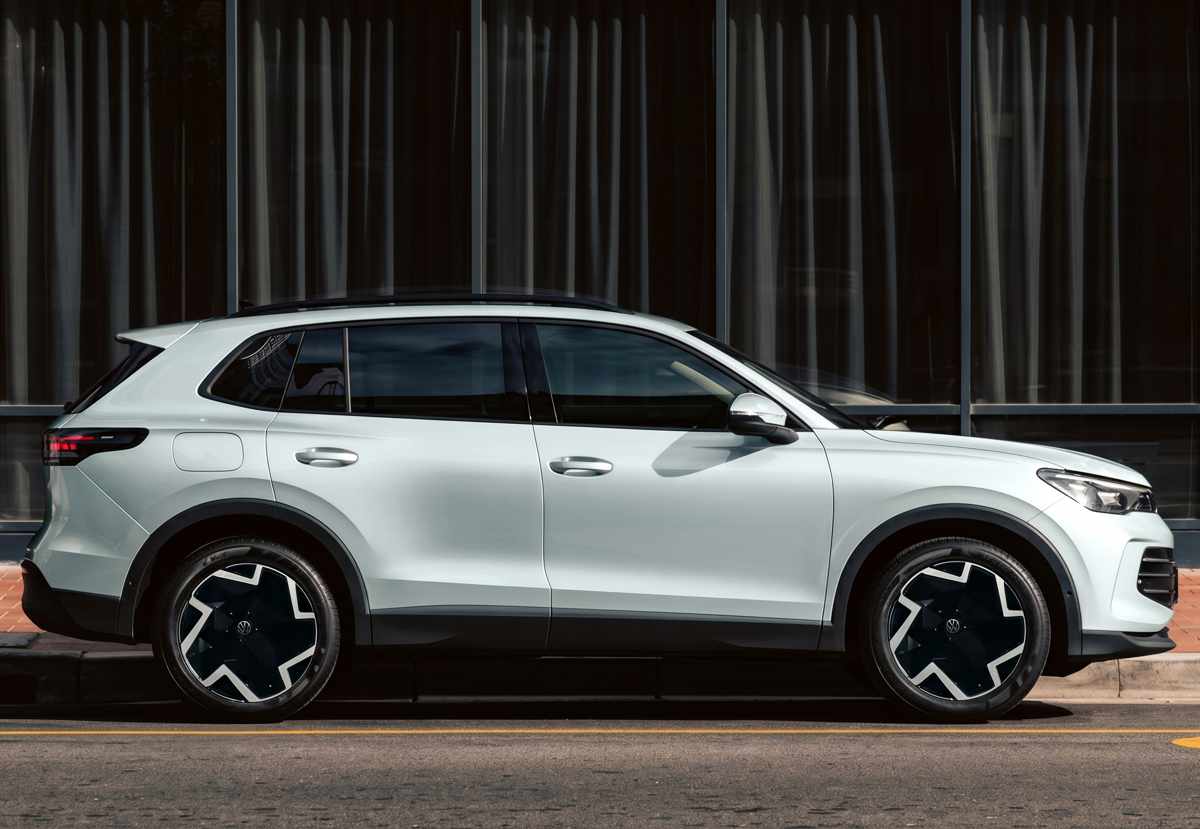 Perfil lateral de la Volkswagen Tiguan e-TSI híbrida blanca estacionada en la ciudad, destacando su silueta de carrocería corta de 4,53 metros de largo y rines bitono de 19 pulgadas.