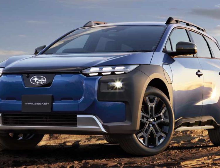 Subaru Trailseeker eléctrica color azul oscuro posando en un terreno rocoso y árido con la ciudad de fondo, destacando su diseño frontal aventurero y faros LED.