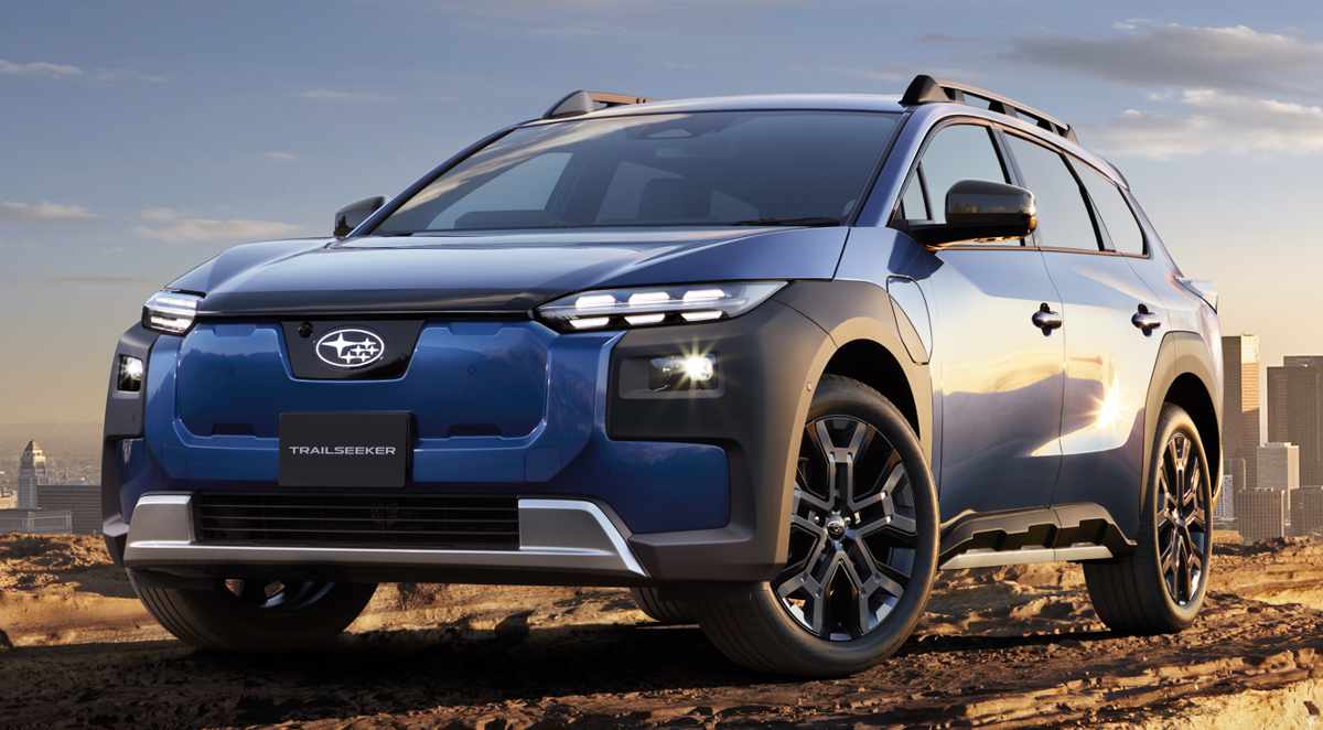 Subaru Trailseeker eléctrica color azul oscuro posando en un terreno rocoso y árido con la ciudad de fondo, destacando su diseño frontal aventurero y faros LED.