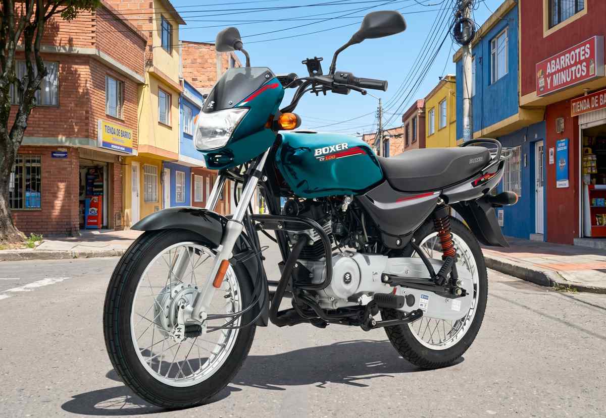 Motocicleta de trabajo Bajaj Boxer CT100 color verde azulado metalizado estacionada en una calle de un barrio tradicional colombiano, destacando su robustez y rines de radios.