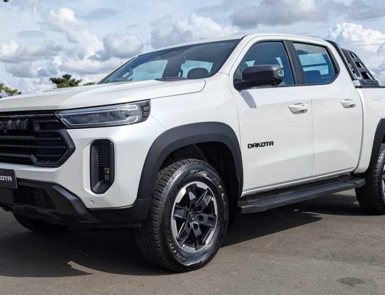 Vista tres cuartos delantera de la nueva pick-up RAM Dakota color Blanco Glaciar, destacando su parrilla frontal oscura y diseño robusto, estacionada a plena luz del día.