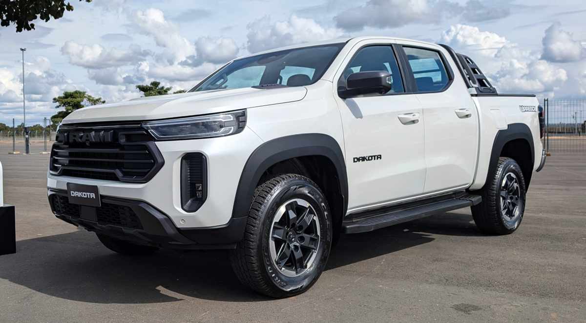Vista tres cuartos delantera de la nueva pick-up RAM Dakota color Blanco Glaciar, destacando su parrilla frontal oscura y diseño robusto, estacionada a plena luz del día.