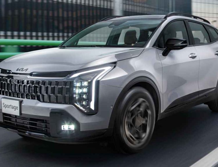 Camioneta Kia Sportage color plata en movimiento por una vía urbana moderna, destacando sus luces LED diurnas y diseño frontal.