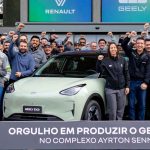Grupo de directivos y trabajadores celebrando junto al carro eléctrico Geely EX2 color verde claro en el Complejo Ayrton Senna en Brasil, con logotipos de Renault y Geely en el fondo y un cartel conmemorativo de su producción sudamericana.