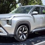 Vista tres cuartos delantera de la nueva camioneta de siete puestos Mitsubishi Destinator color Plata Metalizado, exhibida sobre una tarima reflectiva en Colombia.