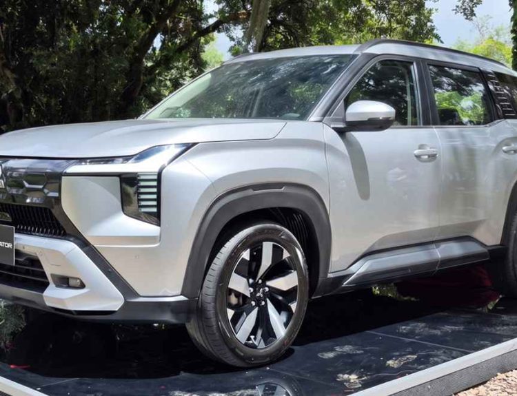 Vista tres cuartos delantera de la nueva camioneta de siete puestos Mitsubishi Destinator color Plata Metalizado, exhibida sobre una tarima reflectiva en Colombia.