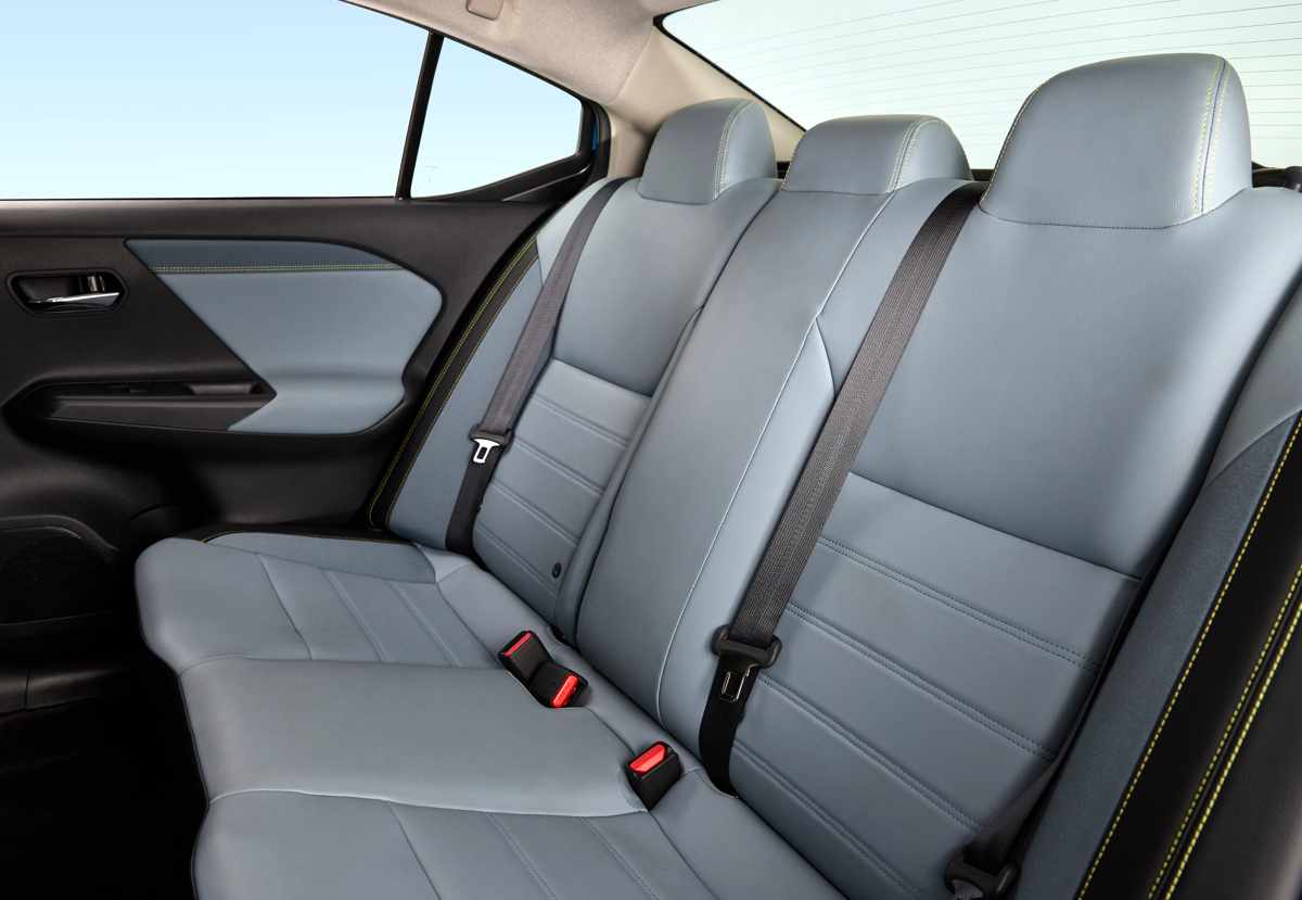 Amplia banca trasera de pasajeros del nuevo Nissan Versa 2027, mostrando los acabados de la cojinería en tonos grises y los cinturones de seguridad.