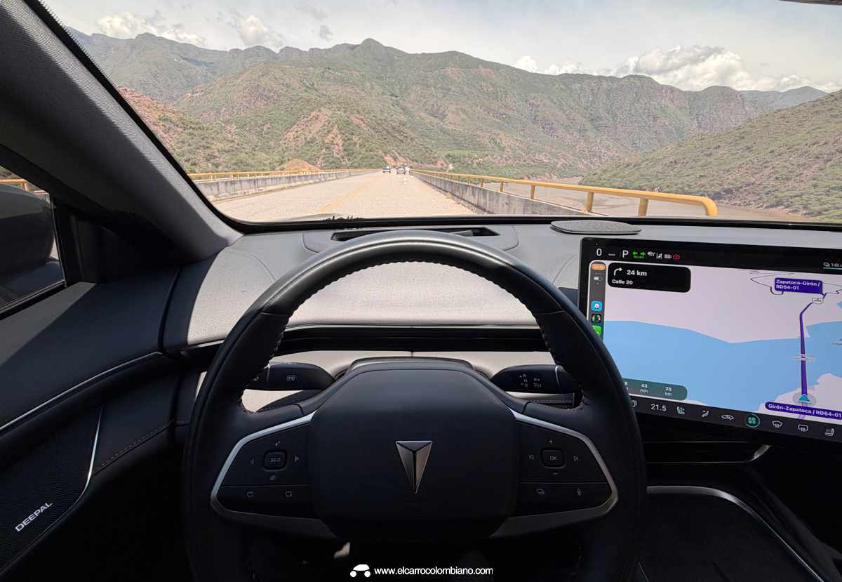 Perspectiva interior desde el puesto de conducción de la Deepal S07, mostrando el volante multifunción y el recorrido de la carretera cruzando el puente sobre el río Sogamoso.