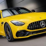 Un Mercedes-AMG GT 43 color amarillo avanzando a toda velocidad, destacando su parrilla frontal y diseño aerodinámico deportivo sobre un fondo oscuro en movimiento.