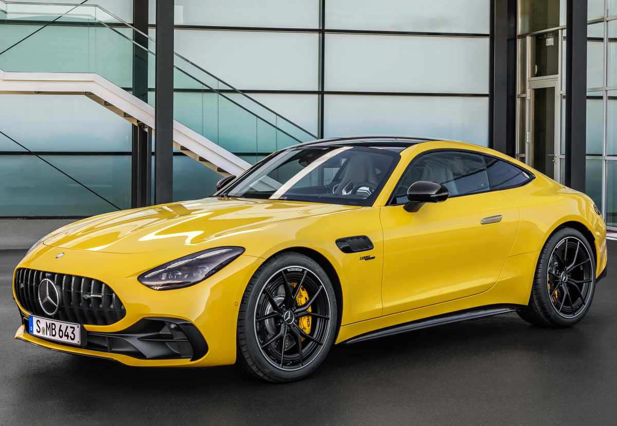 Vista frontal de tres cuartos del Mercedes-AMG GT 43 amarillo estacionado frente a la arquitectura de un edificio moderno con acabados en cristal.