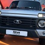 Vista frontal detallada del renovado Lada Niva Legend 2026 color plata exhibido en un evento, destacando su clásica parrilla negra, faros redondos y la nueva toma de aire funcional sobre el capó.
