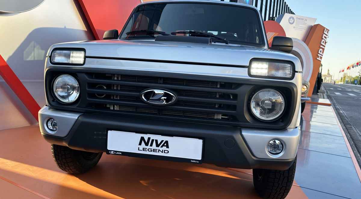 Vista frontal detallada del renovado Lada Niva Legend 2026 color plata exhibido en un evento, destacando su clásica parrilla negra, faros redondos y la nueva toma de aire funcional sobre el capó.