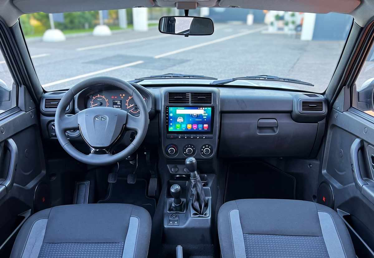 Interior de la cabina del nuevo Lada Niva Legend 2026, exhibiendo la inédita pantalla táctil multimedia central, el volante moderno heredado del Lada Granta y la palanca de cambios reubicada.