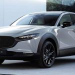 Vista frontal de tres cuartos de la renovada Mazda CX-30 2027 luciendo el inédito color exterior Gris Aéreo, destacando su gran parrilla negra y faros LED afilados.