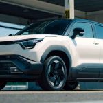 Vista frontal de tres cuartos del nuevo SUV eléctrico Suzuki e-Vitara color blanco brillante, destacando su diseño robusto, faros LED y rines aerodinámicos bajo luz natural.