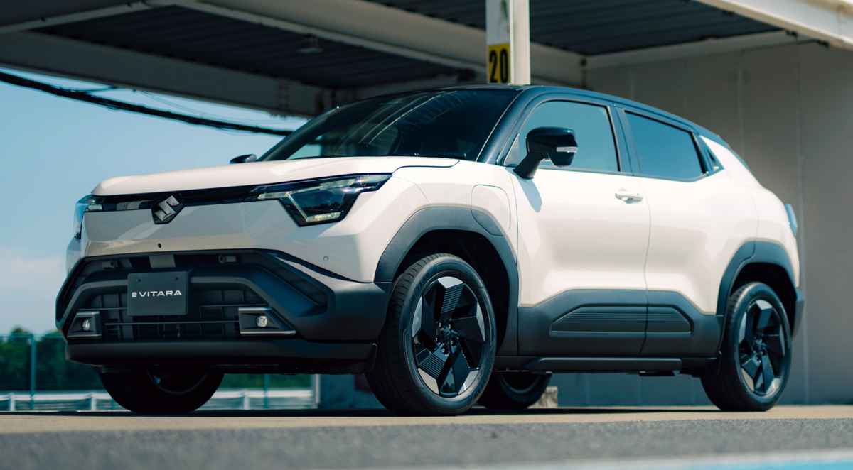 Vista frontal de tres cuartos del nuevo SUV eléctrico Suzuki e-Vitara color blanco brillante, destacando su diseño robusto, faros LED y rines aerodinámicos bajo luz natural.