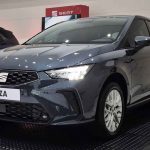 Vista frontal de tres cuartos del renovado hatchback SEAT Ibiza Style color Gris Magnético, exhibido en vitrina y destacando su nueva parrilla hexagonal y faros LED.