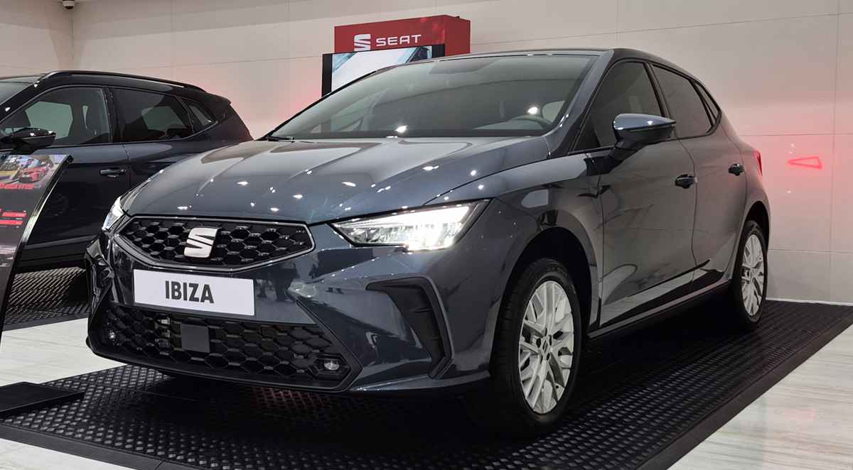 Vista frontal de tres cuartos del renovado hatchback SEAT Ibiza Style color Gris Magnético, exhibido en vitrina y destacando su nueva parrilla hexagonal y faros LED.