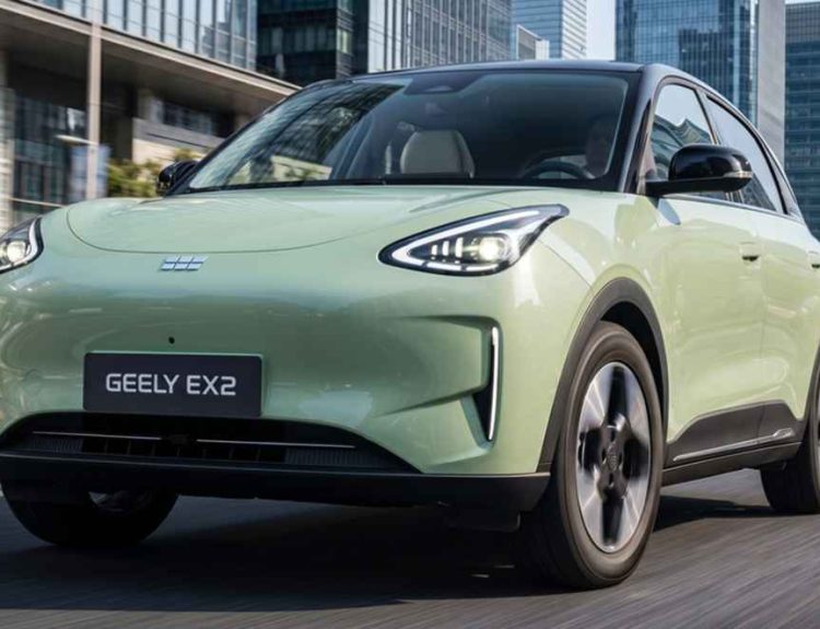 Vista frontal en movimiento del hatchback eléctrico Geely EX2 color verde claro recorriendo una amplia vía urbana, destacando su diseño aerodinámico de líneas limpias y luces diurnas afiladas.