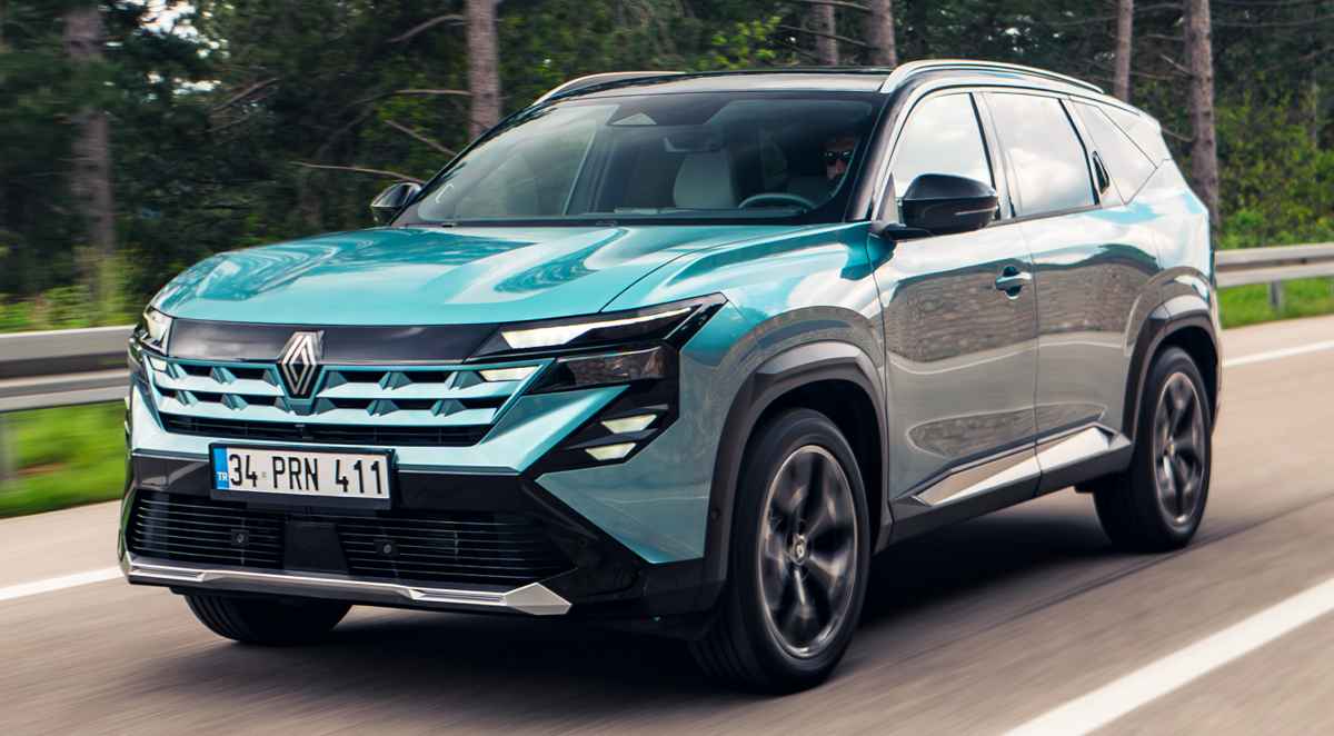 Vista frontal en movimiento de la nueva camioneta Renault Boreal Híbrida 4x4 color azul turquesa recorriendo una carretera, destacando su firma lumínica LED y parrilla frontal.