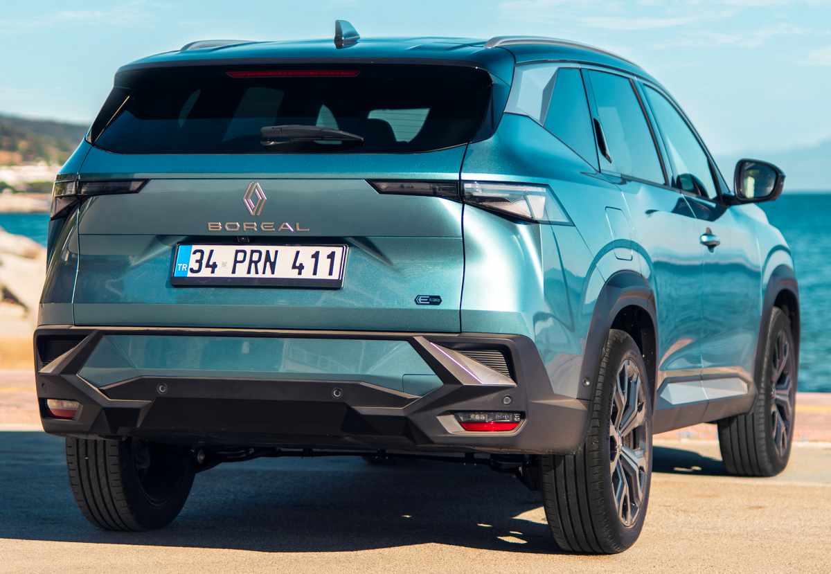 Vista posterior estática de la Renault Boreal Híbrida estacionada frente al mar, enfocando su robusto bumper inferior, el nombre del modelo y el emblema de la tecnología E-Tech.