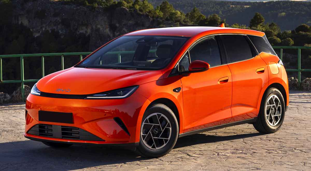 Vista frontal de tres cuartos del nuevo BYD Dolphin G DM-i híbrido enchufable color naranja estacionado en una carretera, destacando su nuevo capó horizontal, parrilla cerrada y luces LED afiladas.