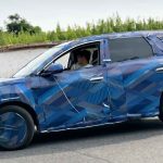 Vista de perfil en marcha de la nueva generación del BYD Tang cubierta con un denso camuflaje azul con patrones geométricos durante pruebas de ruta en China.