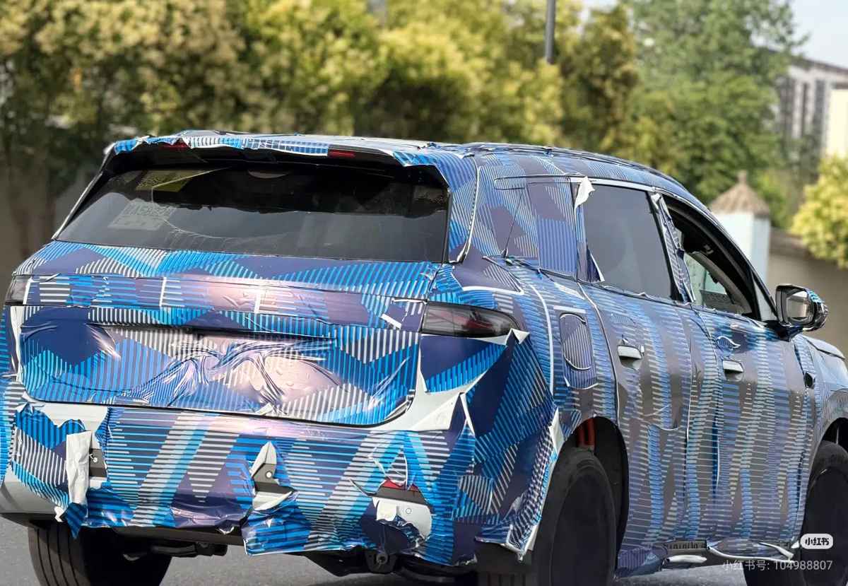 Vista trasera de tres cuartos del prototipo camuflado de la próxima BYD Tang, dejando ver sus formas de SUV grande y la caída del pilar trasero.