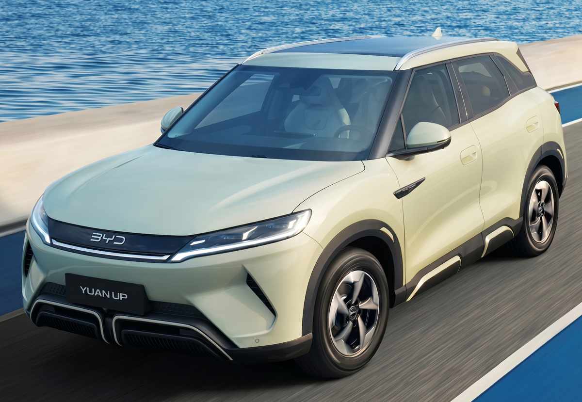 Camioneta eléctrica BYD Yuan Up de color verde claro rodando por una carretera junto al mar, destacando como uno de los modelos de nuevas energías más exitosos en los mercados de Colombia y Uzbekistán en 2026.