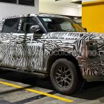 Vista lateral y frontal de tres cuartos de la nueva pick-up Nissan Frontier Pro híbrida enchufable cubierta con camuflaje de cebra, estacionada en un parqueadero en Bucaramanga durante sus pruebas de ruta.